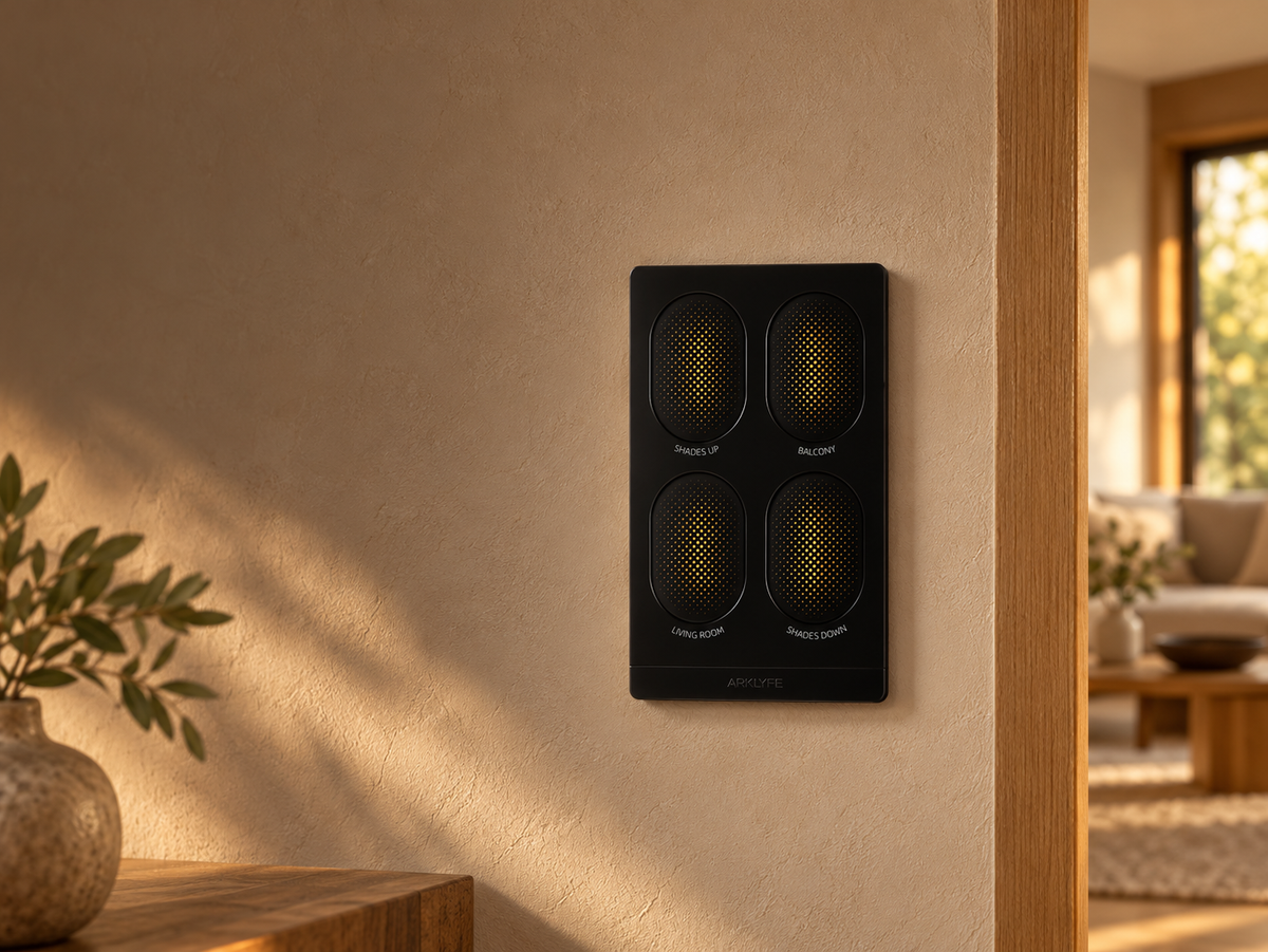 Black four-button Arklyfe StellarTrack switch on a warm plaster wall beside oak joinery.